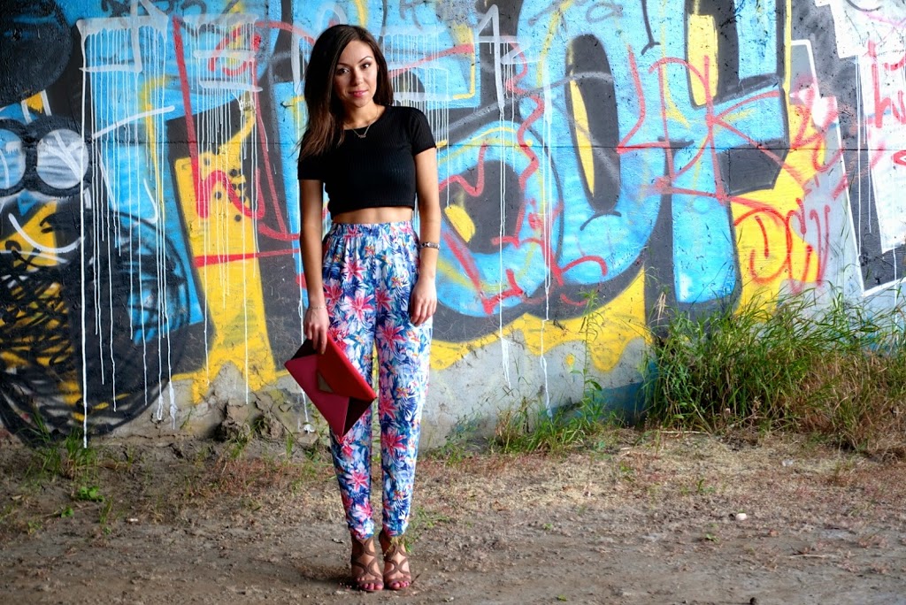 Blogger Nihan posing in front of a graffiti wall, wearing floral print harem pants, black crop top and high-heels