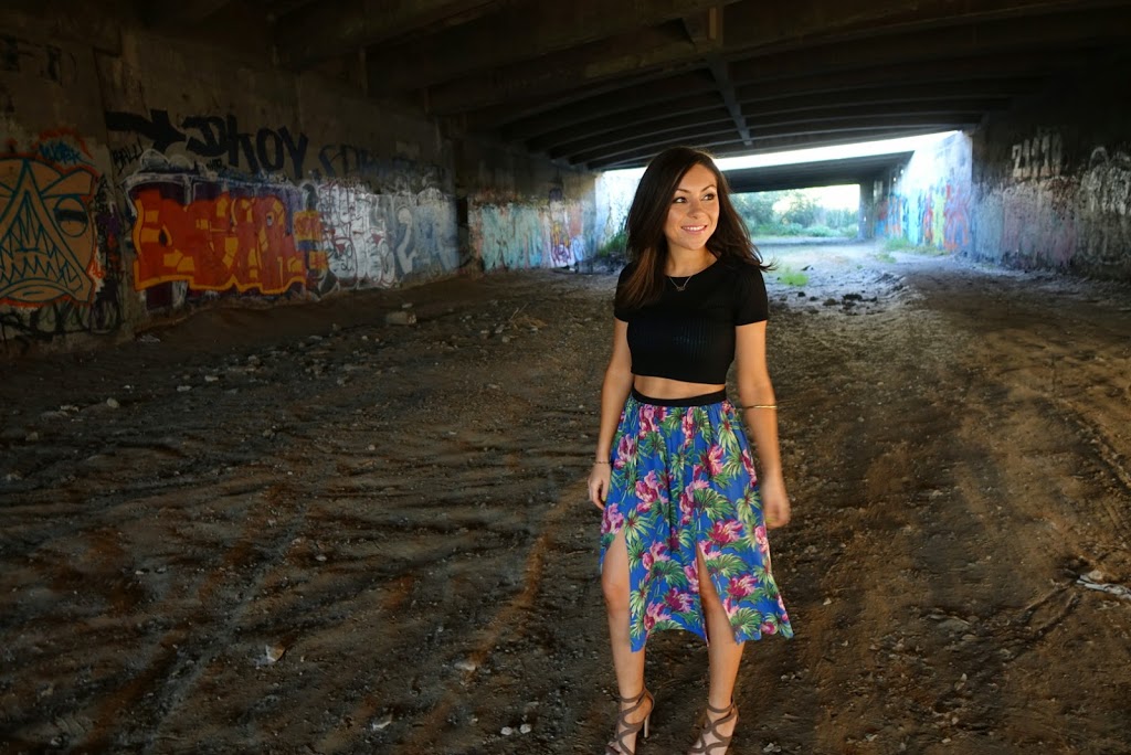 Blogger Nihan posing in front of a graffiti wall and showing her outfit: a floral midi skirt by Topshop and a black crop top